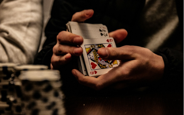 A player shuffling a deck of cards with some poker chips on the table. 